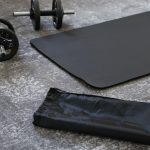 a pair of dumbbells and a black mat on the floor